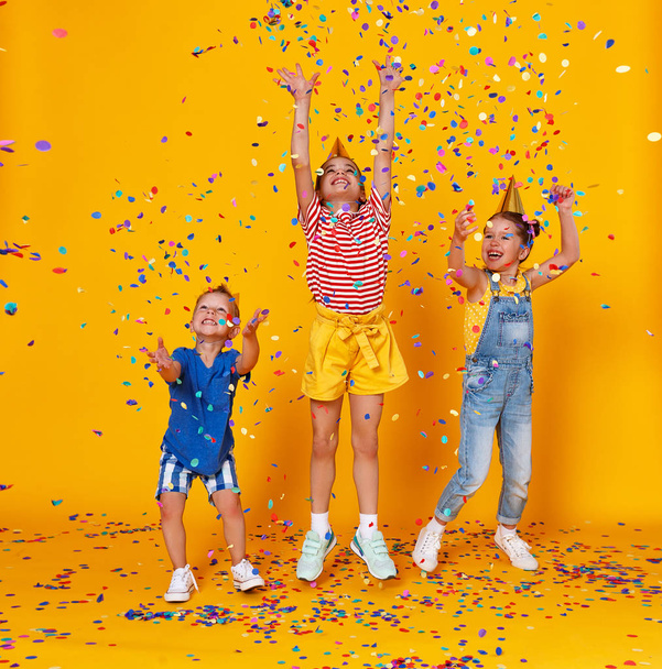 fröhliche Kinder im Urlaub springen in buntem Konfetti auf  - Foto, Bild