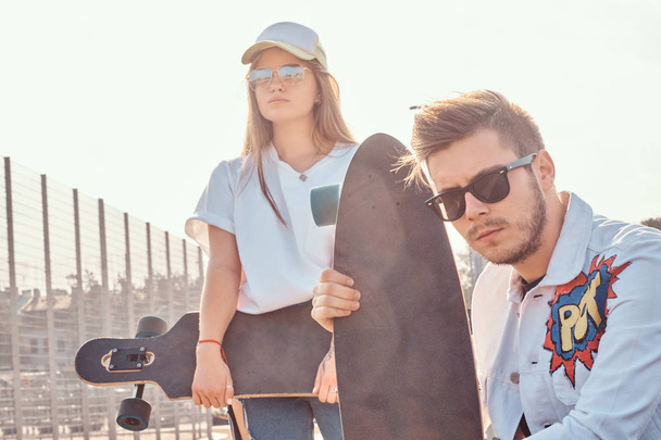 Mladý trendy pár je chilling na slunné ulici s jejich longboardy - Fotografie, Obrázek