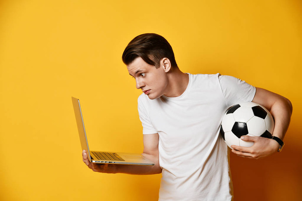 Young man with laptop and a soccer ball - 写真・画像