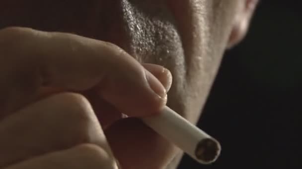Raucher zündet sich Zigarette vor schwarzem Hintergrund an - Filmmaterial, Video
