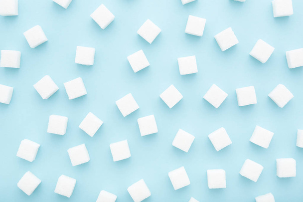 Mavi arka plan üzerine dağılmış şeker küplerinden oluşan soyut desen - Fotoğraf, Görsel