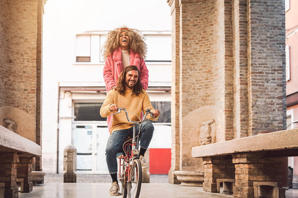 市内中心部で自転車に乗る幸せなカップル - 若者がアウトドアを楽しむ - ミレニアル世代と若者のライフスタイルコンセプト - 写真・画像