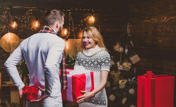Woman and man are giving Christmas gifts to each other. Lovely happy couple. - Foto, immagini