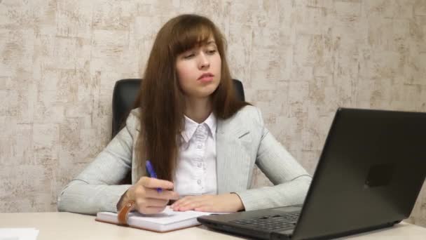 mooi meisje zittend in een stoel in kantoor en het praten en het maken van aantekeningen in bloknot. jonge vrouwelijke ondernemer werkt met een client in een kantoor - Video