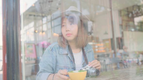 Podnikání na volné noze asijských žena pít teplý šálek zeleného čaje nebo kávy zatímco sedí na stole v kavárně. Životní styl inteligentní krásná žena relaxovat v kavárně pojmy. - Fotografie, Obrázek