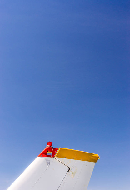 Staartvinnen, roer-en zwaailichten, kleine éénmotorige vliegtuig met oude verf en helder blauwe hemel. - Foto, afbeelding