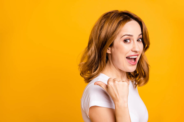 Close up side profile photo beautiful amazing she her pretty lady arm hand thumb finger indicate empty space look what I have short hairdo wear casual white t-shirt isolated yellow background - Foto, Imagen
