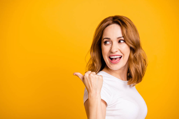 Close up side profile photo beautiful amazing she her pretty lady look arm hand thumb finger indicate empty space look what I have short hairdo wear casual white t-shirt isolated yellow background - Foto, Imagen