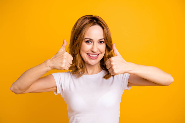 Close up photo beautiful toothy pretty she her lady hold arms hands thumb fingers up short hairstyle amazed excited advising buy buyer new product wear casual white t-shirt isolated yellow background - Photo, image