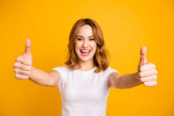 Close up photo beautiful pretty she her foxy lady hold arms hands thumb fingers up short hairstyle amazed excited advising buy buyer new product wear casual white t-shirt isolated yellow background - Fotó, kép