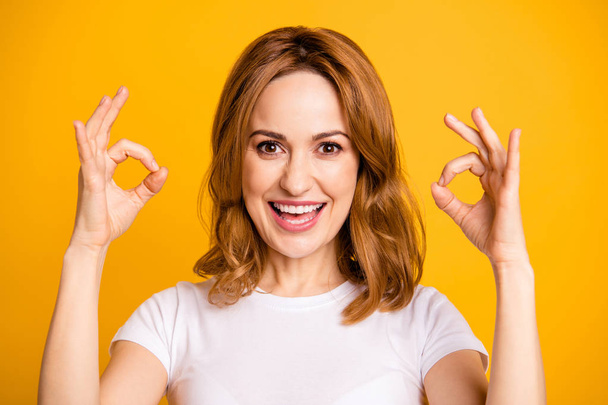 Close up photo beautiful amazing she her foxy lady arm hand fingers okey symbol short hairstyle amazed excited advising buy buyer new product wear casual white t-shirt isolated yellow background - Foto, immagini