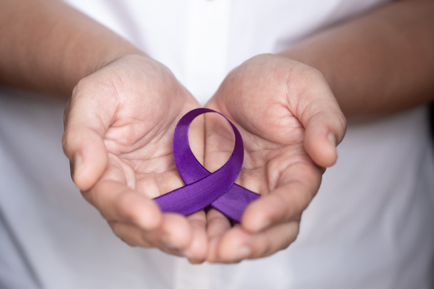womans hands holding purple domestic violence awareness ribbon - Φωτογραφία, εικόνα
