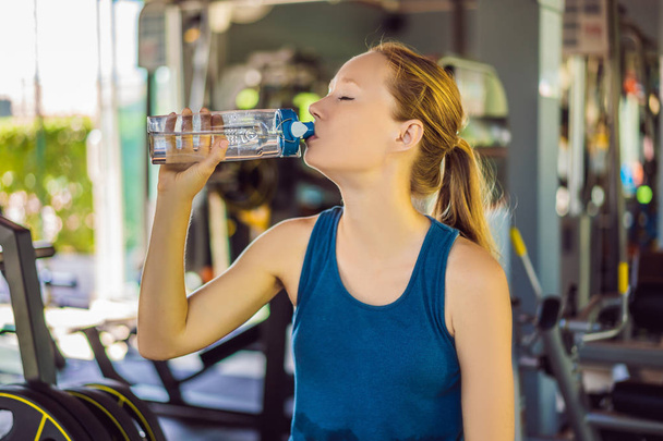 Young athletic woman drinking water in gym - Foto, Bild