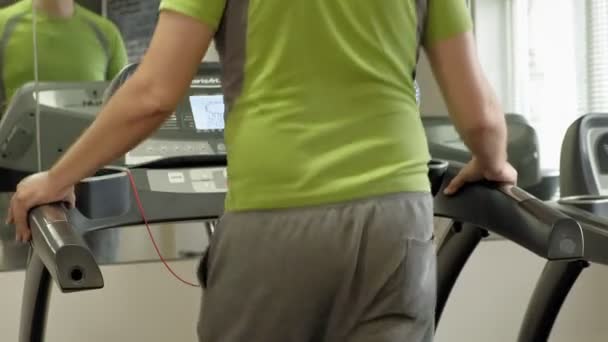 Um homem com excesso de peso numa passadeira num ginásio. Aptidão. Estilo de vida saudável
 - Filmagem, Vídeo