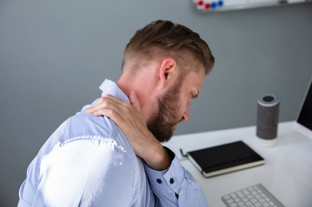 Businessman Suffering From Neck Pain At Desk - Фото, зображення