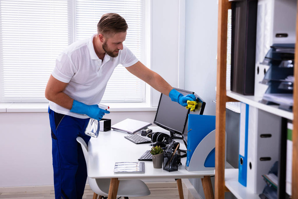 Janitor cleaning white desk in modern office - Photo, image