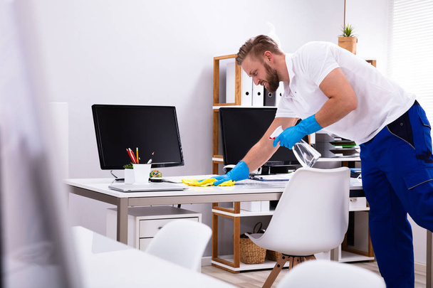 Janitor cleaning white desk in modern office - Foto, Bild