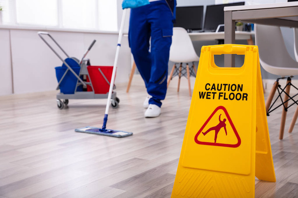 Male janitor with mop cleaning modern office floor - Foto, Bild