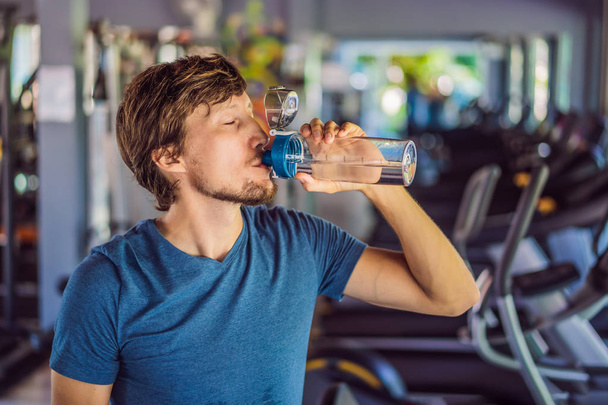 Sport man drinking water in the gym - Foto, afbeelding