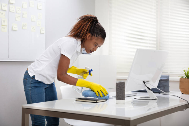 Young Female Janitor Cleaning Desk With Napkin In Office - Foto, immagini