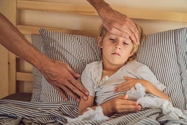 Sick boy with thermometer laying in bed and father hand taking temperature. father checking temperature of her sick son who has thermometer. Sick child with fever and illness in bed - Foto, Imagem