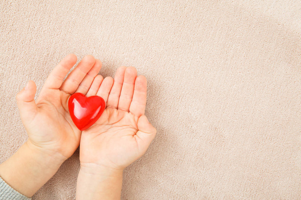Mãos de criança segurando coração vermelho
 - Foto, Imagem