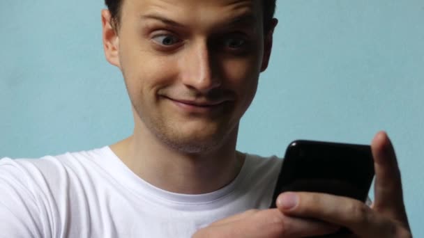 The man is surprised and smiles from the received message or news read on the phone. Close-up. The shot is fixed on the man - Záběry, video