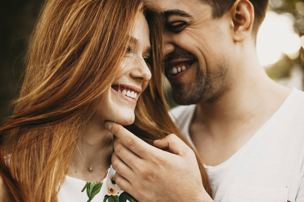 Lähikuva muotokuva kaunis nuori valkoihoinen pari hauskaa hymyillen kun mies koskettaa hänen tyttöystävänsä kasvot, kun hän katsoo pois hymyillen
. - Valokuva, kuva