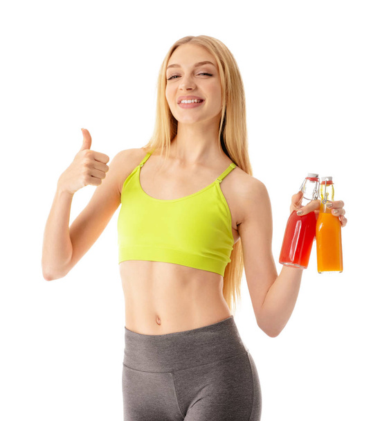 Sportos fiatal nő, üveg gyümölcslé mutatja hüvelykujj-up fehér alapon - Fotó, kép