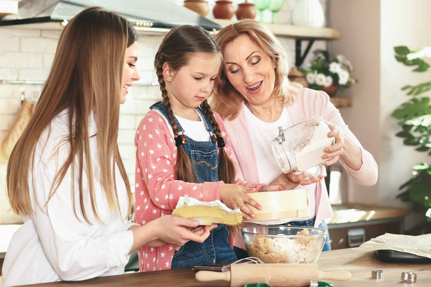 Kleines Mädchen mit Mutter und Großmutter beim Plätzchenbacken in der heimischen Küche - Foto, Bild