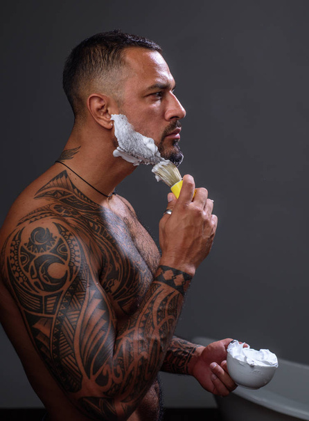 Man shaving. Feeling fresh after shaving. brutal sportsman washing in bath. steroids. sport and fitness, health. muscular macho man with athletic body. sexy tattoo man hold sponge with soap foam - Foto, imagen