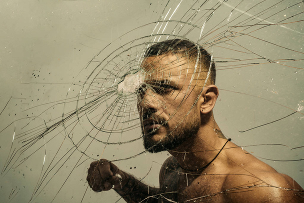 Determination to succeed. Muscular man having inner determination and commitment to break glass wall. Determined latino man removing obstacle with determination and confidence. Determination concept - Foto, imagen