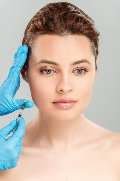 cropped view of cosmetologist holding syringe near face of beautiful and naked woman isolated on grey  - Fotografie, Obrázek