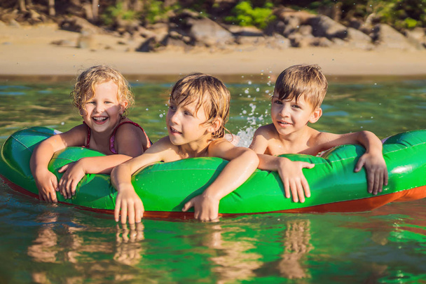 Children swim in the sea on an inflatable mattress and have fun - Fotoğraf, Görsel