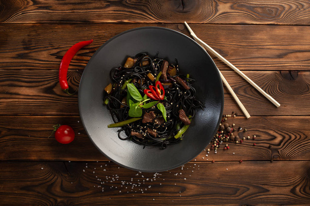 black noodles with marbled beef on a wooden background - Foto, Imagem
