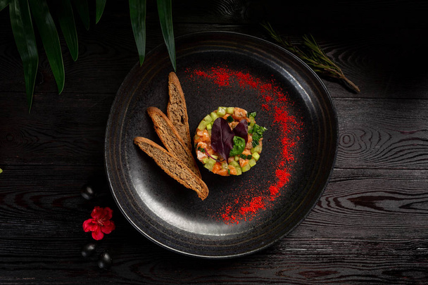 salmon tar-tar with spices on a black plate - Zdjęcie, obraz