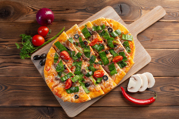 pizza with veal and dried tomatoes on a wooden background - Foto, afbeelding
