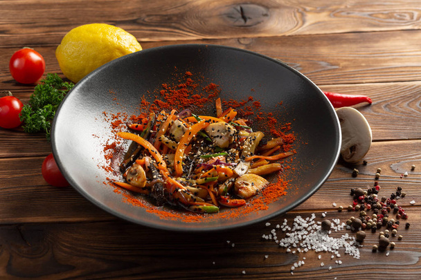 wok vegetables with spices in a black plate - Foto, Bild