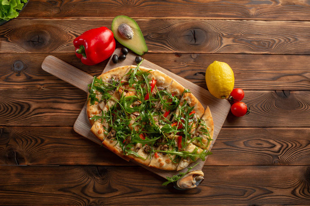 pizza with seafood and arugula on a wooden background - Photo, Image