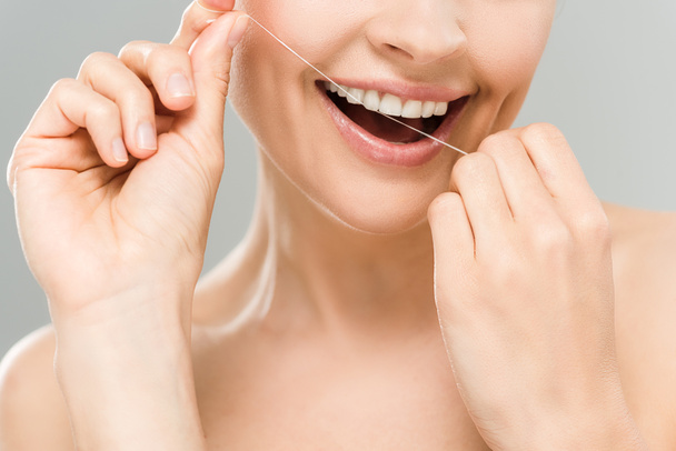 przycięte widok szczęśliwy nagi kobieta zęby Flossing z dentystycznych nici izolowane na szaro  - Zdjęcie, obraz