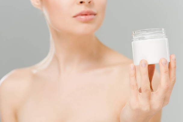 cropped view of naked woman holding container with cosmetic cream isolated on grey  - Foto, Imagem