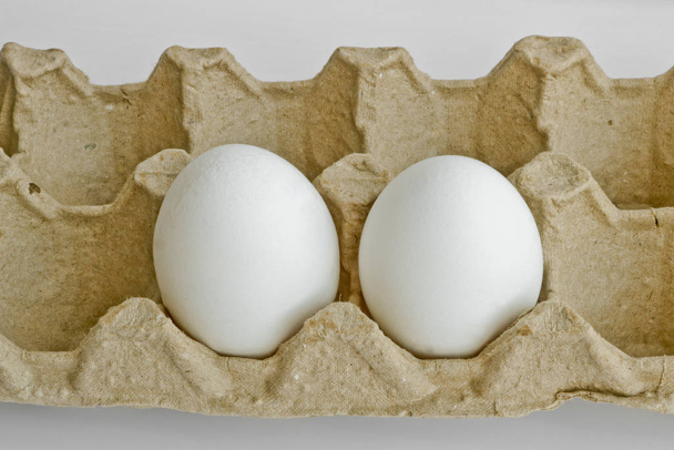 Due uova bianche nella confezione per le uova dell'allevamento di polli. Ultime scorte di uova
. - Foto, immagini