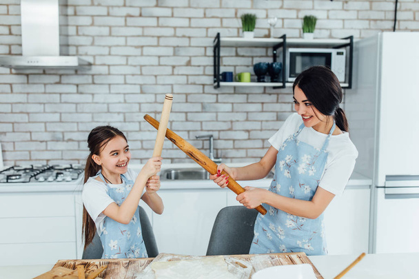 Portrait of two sisters at kitchen cooking and spending time funny - Фото, изображение