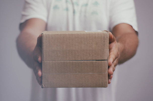 Delivery man with cardboard parcel. Hand holding the delivery box. - Photo, Image