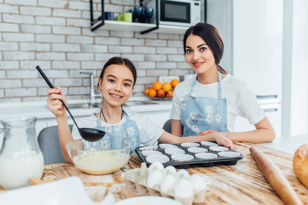 happy sisters cooking cupcakes at kitchen - Фото, зображення