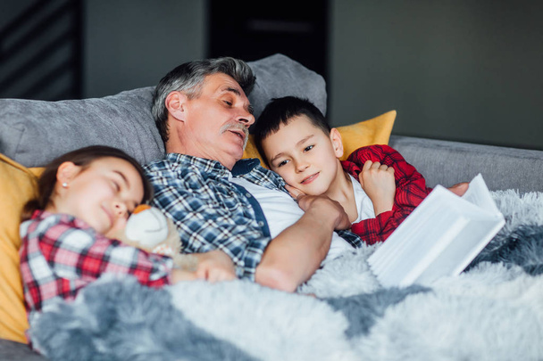 Grandfather and grandchildren reading book at home - Φωτογραφία, εικόνα