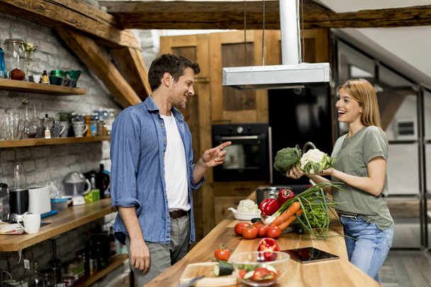 Trendpaar schält und schneidet Gemüse in rustikaler Küche vom Markt - Foto, Bild