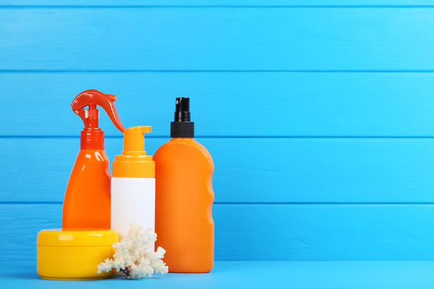 Sunscreen bottles with coral on blue wooden table - Fotografie, Obrázek