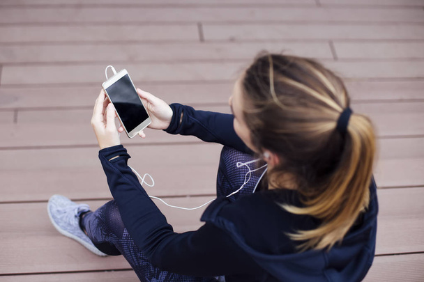 携帯電話を使用し、屋外の階段に座って若いスポーティ女性 - 写真・画像
