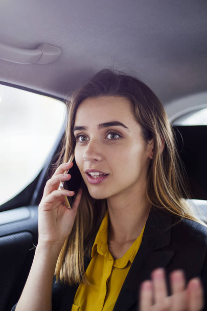 Portrait of young businesswoman talking on mobile phone in car - Foto, afbeelding